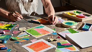 Une personne conçoit une maquette d’affiche dans un atelier, écran volontairement illisible.