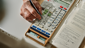 Personne relisant un contrat d’assurance avec une calculatrice sur une table.