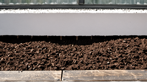 Des mains gantées préparent un mélange de substrat dans une jardinière sur un balcon.
