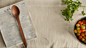 Personne préparant une liste de courses avec un panier de produits du quotidien.