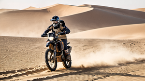 Pilote de rallye-raid sur une moto dans le désert avec sable soulevé