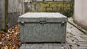 Bacs de tri dans une cour d'immeuble avec une personne tenant un emballage.