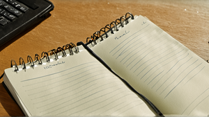 Un cahier et un ordinateur sur un bureau d’élève, en situation de travail.