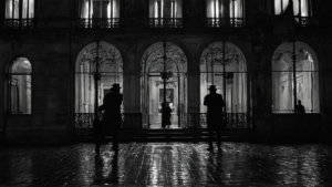 Façade d’un musée éclairée la nuit, avec quelques silhouettes au loin.