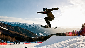 Un snowboarder en plein saut au-dessus d'une rampe dans un snowpark.