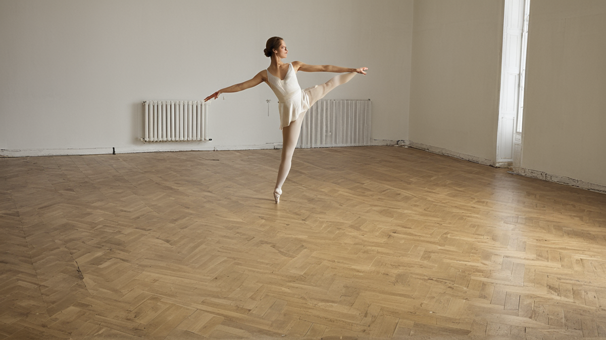 Une ligne de danseuses travaille l’alignement dans une salle de répétition.