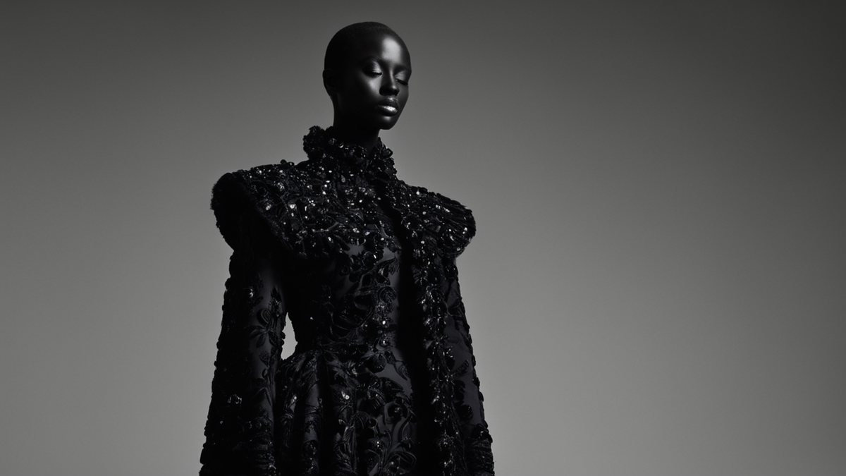 Une silhouette de couture noire à relief surréaliste présentée dans un espace muséal.
