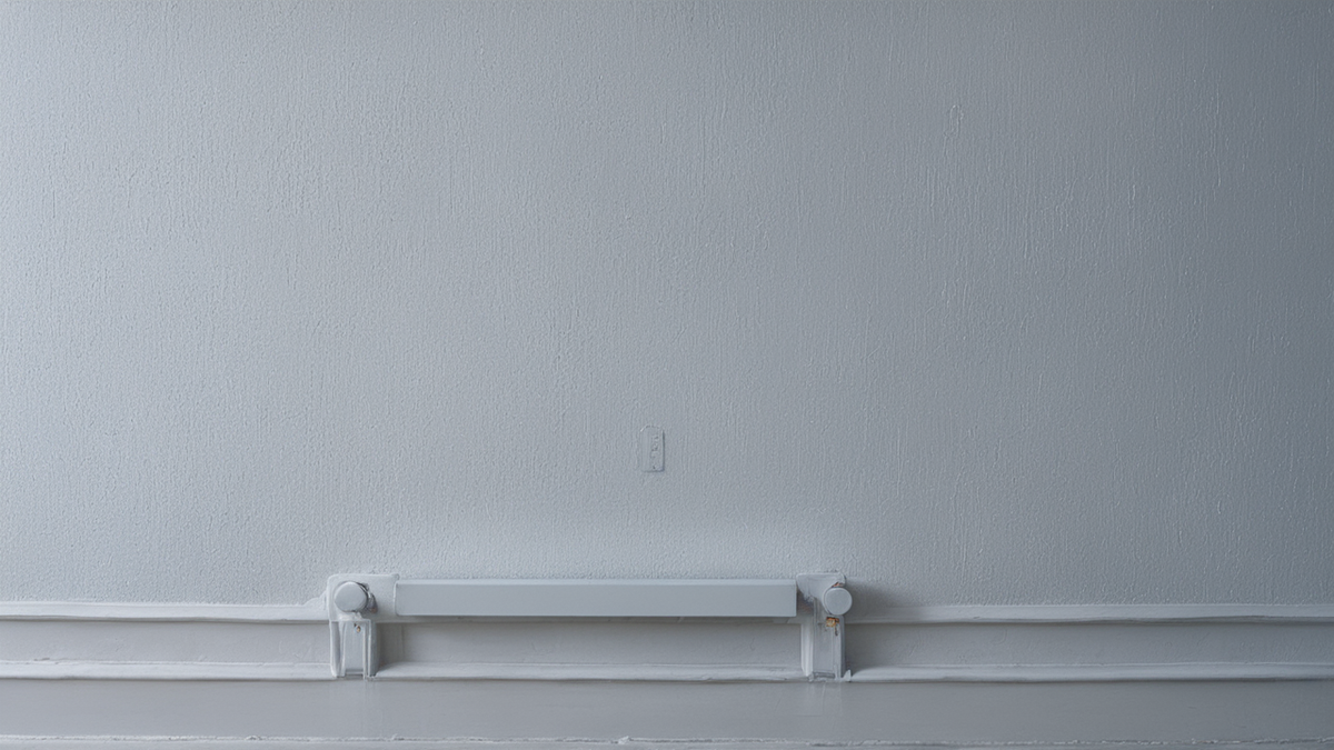 Un thermostat mural éteint dans une pièce de vie en soirée.