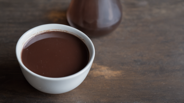 Tasse de chocolat chaud posée sur un comptoir de café sombre.