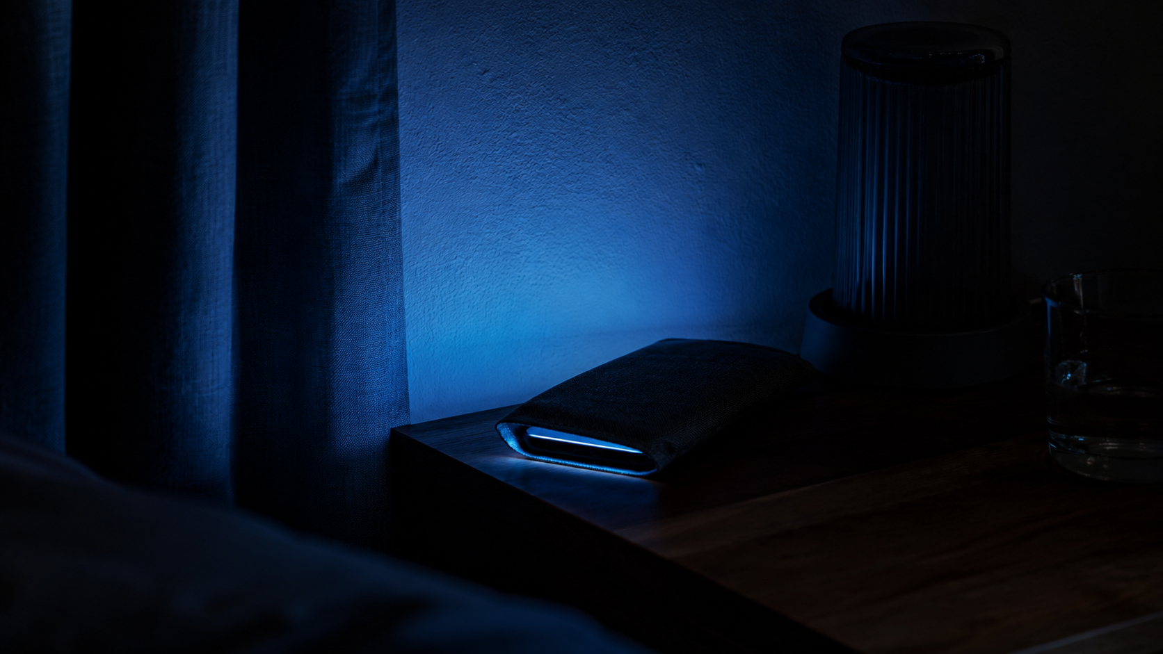 Halo bleu discret d'un téléphone retourné sur une table de chevet.