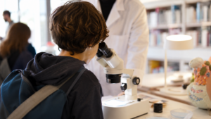 Un atelier de culture scientifique avec microscope dans une médiathèque, sans visage identifiable.