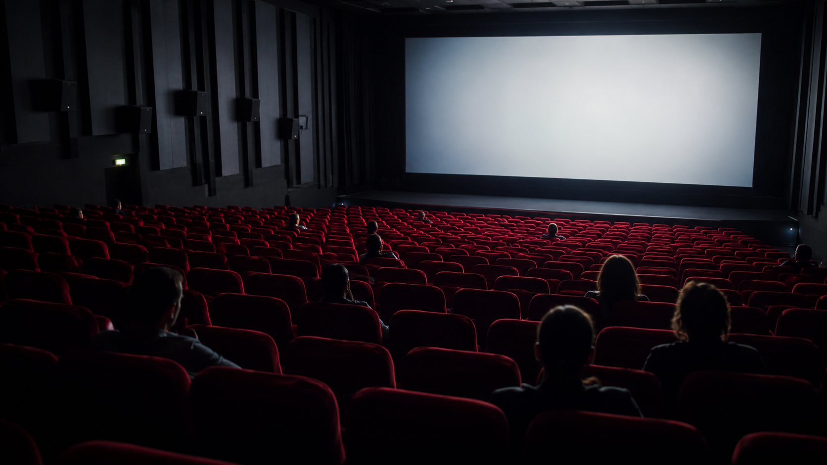 Salle de cinema a moitie vide en seance de jour, fauteuils rouges et ecran clair