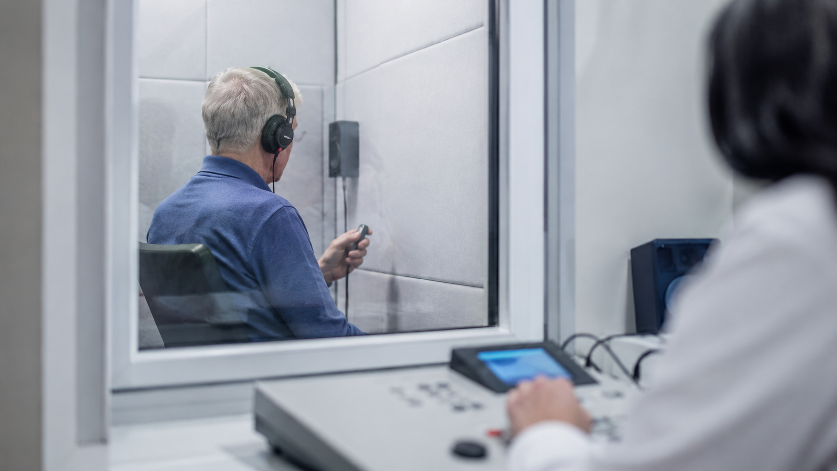Personne âgée passant un test auditif au casque dans une cabine insonorisée