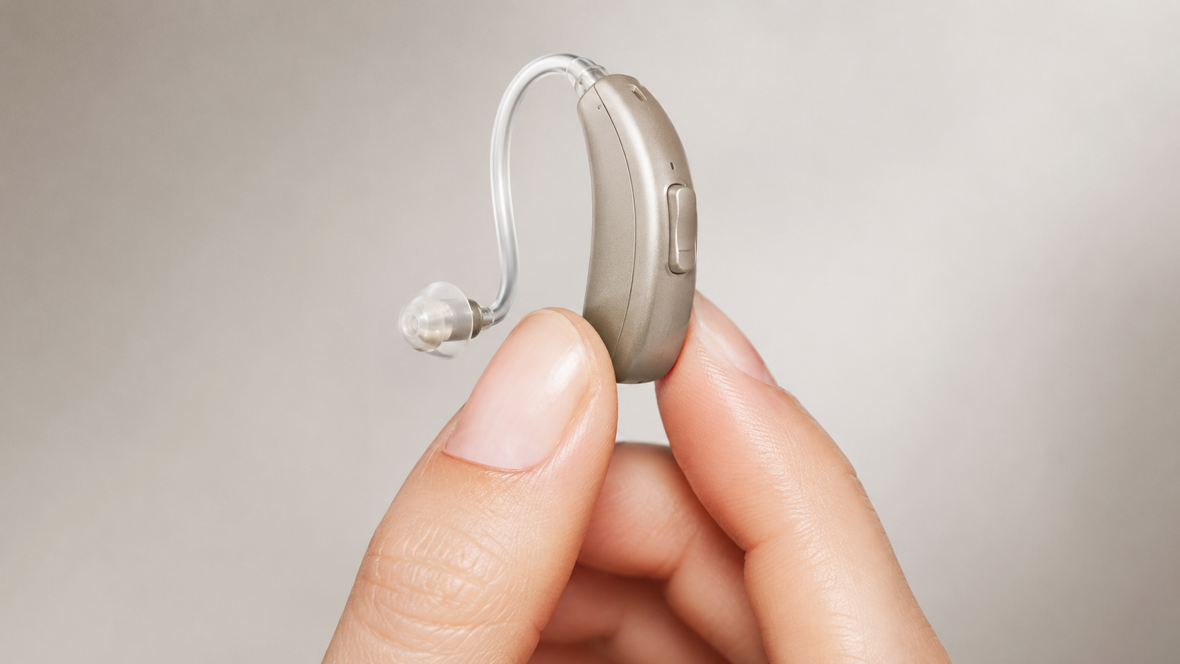 Gros plan d'une petite aide auditive contour d'oreille tenue entre deux doigts