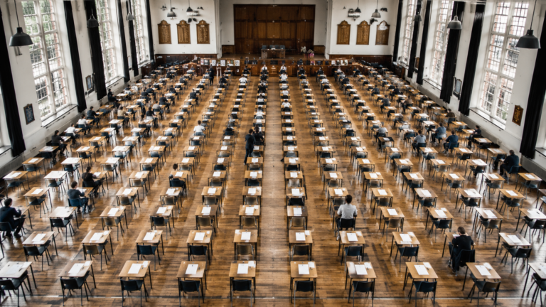 Vaste salle d'examen avec des rangées de pupitres alignés et des copies vierges