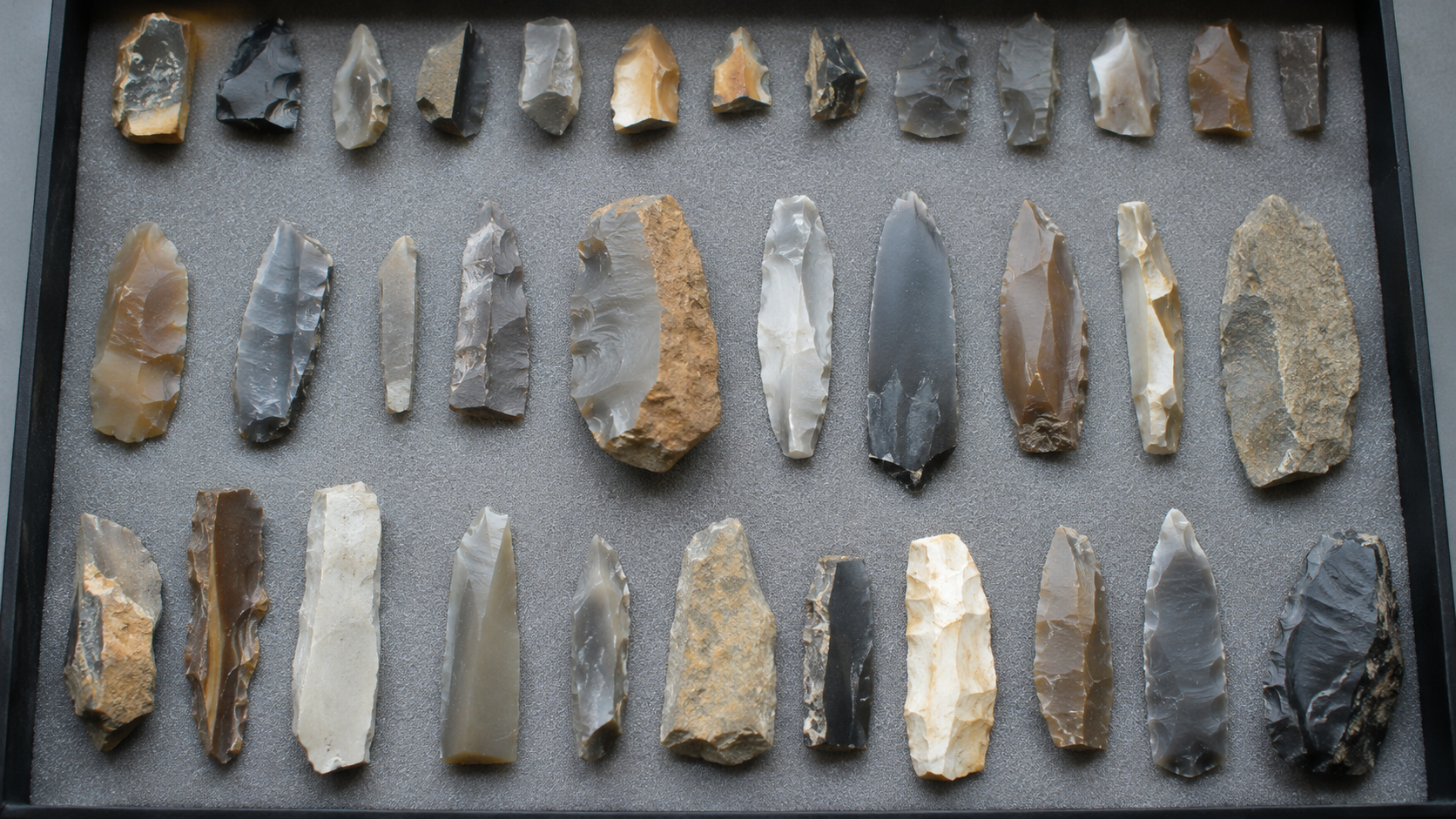 Outils et eclats de silex mesolithiques disposes sur un plateau d'etude archeologique