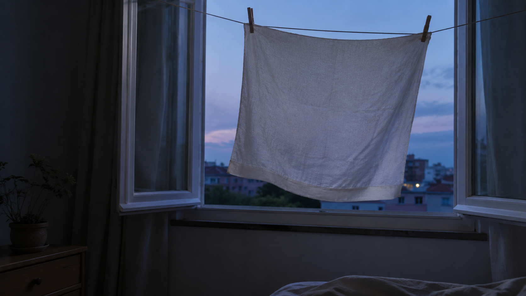 Un linge humide suspendu devant une fenêtre ouverte au crépuscule