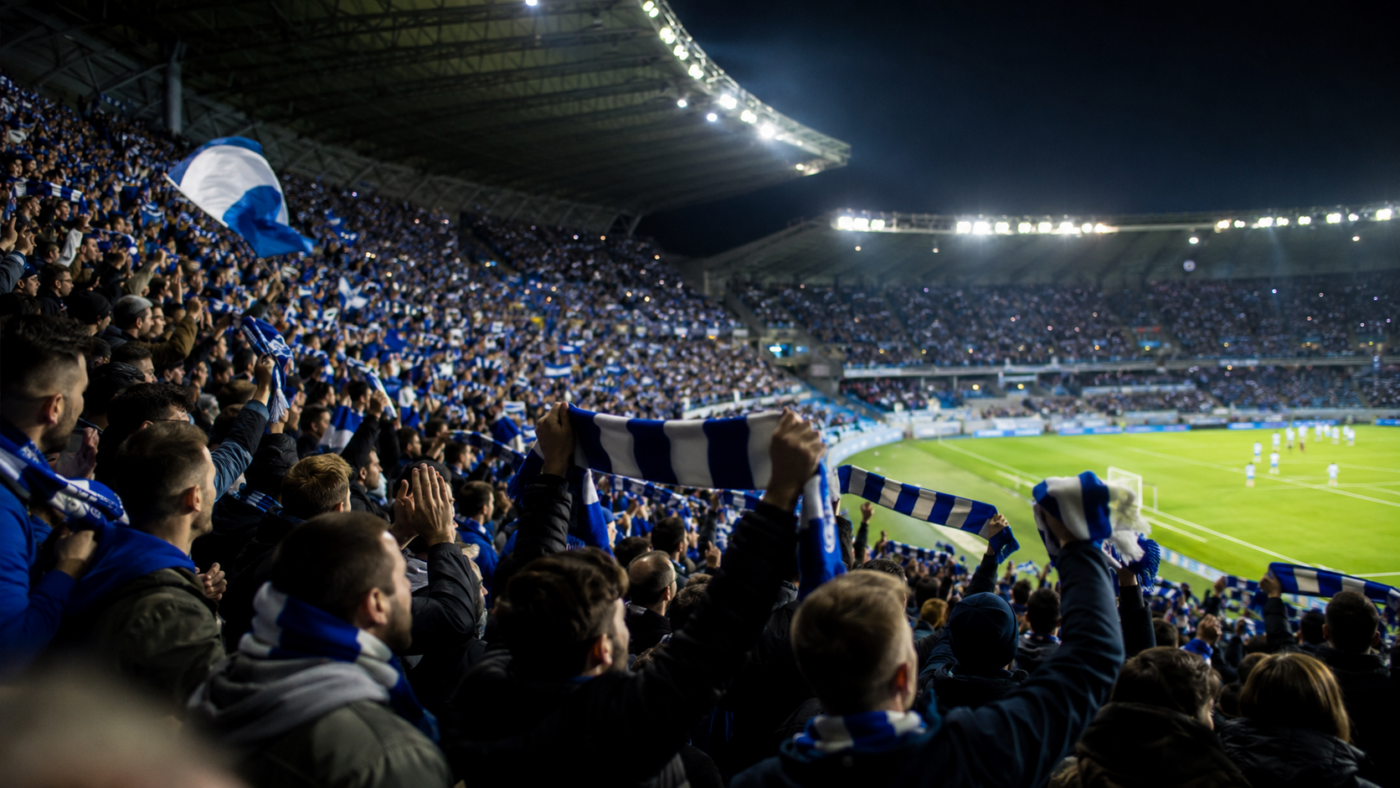 Tribune comble de supporters en liesse agitant des écharpes bleu et blanc dans un stade illuminé la nuit
