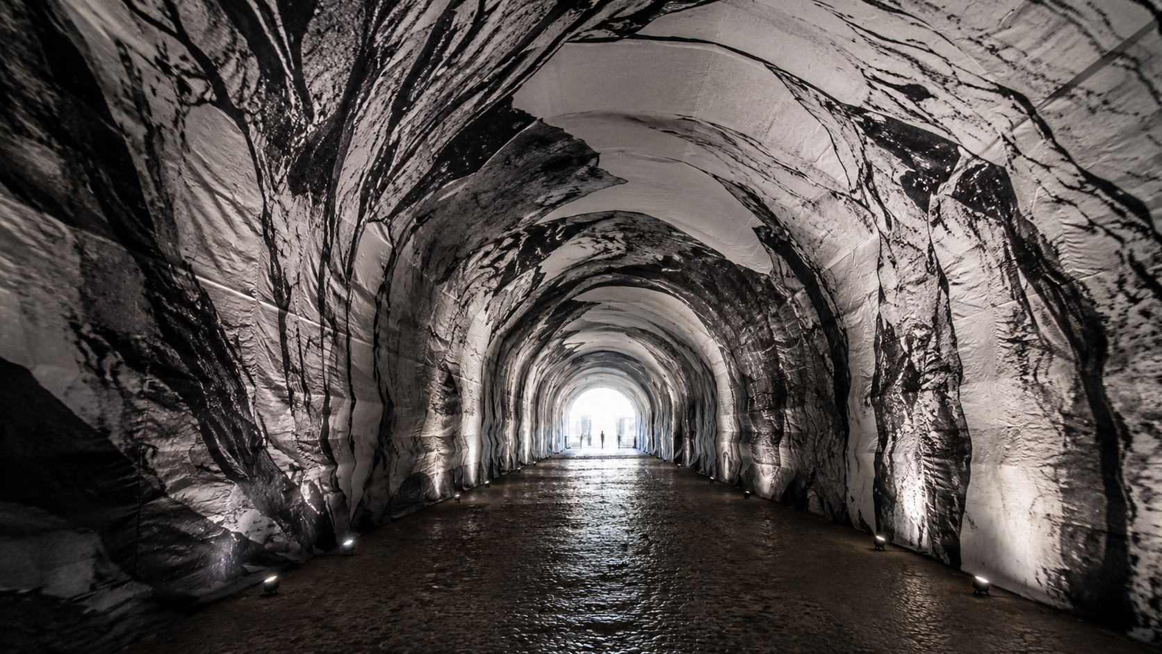 Intérieur sombre d'un tunnel en toile imprimée évoquant une caverne, une lumière au fond
