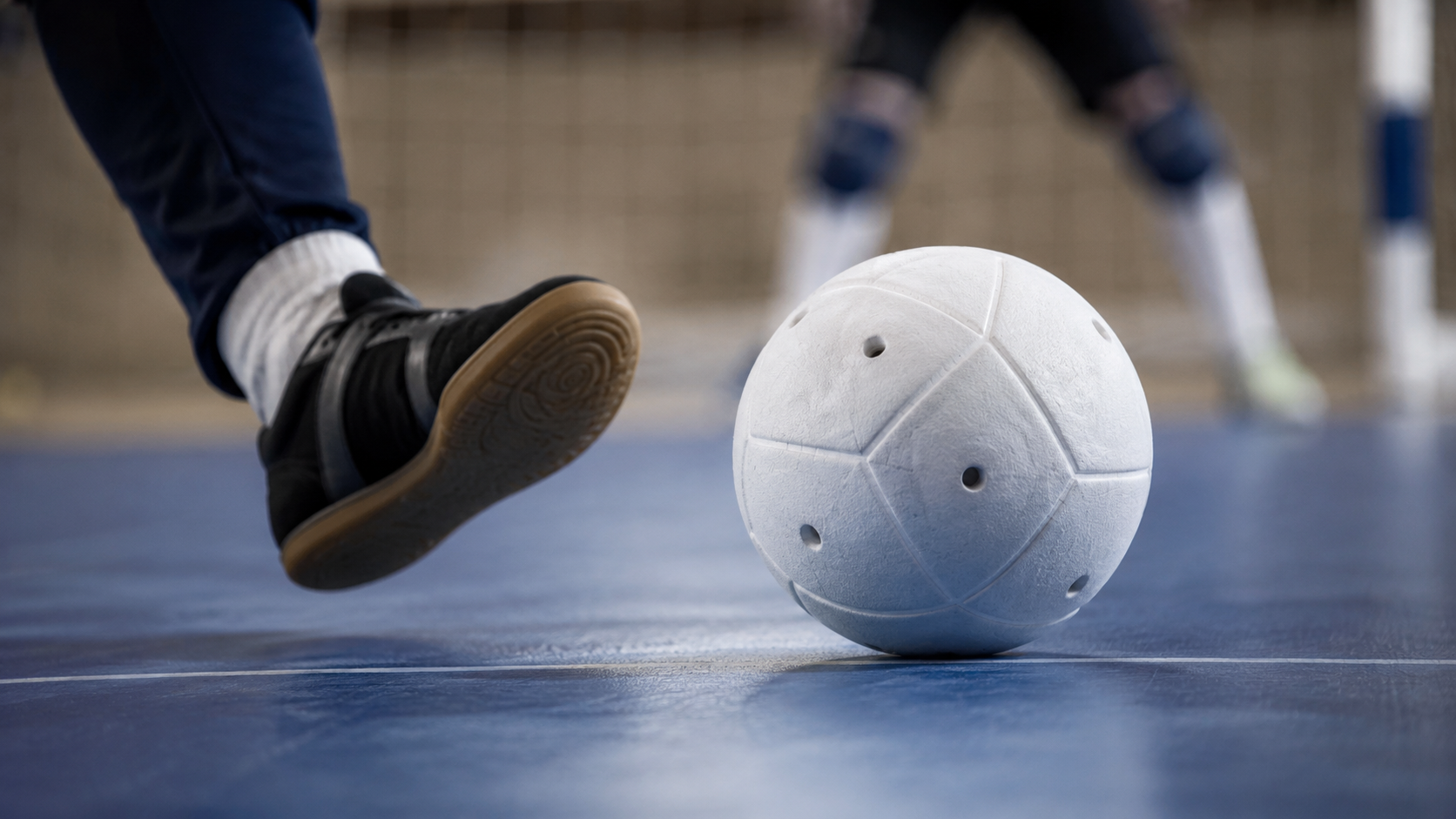 Gros plan sur un ballon de cecifoot a grelots au sol et un pied de joueur