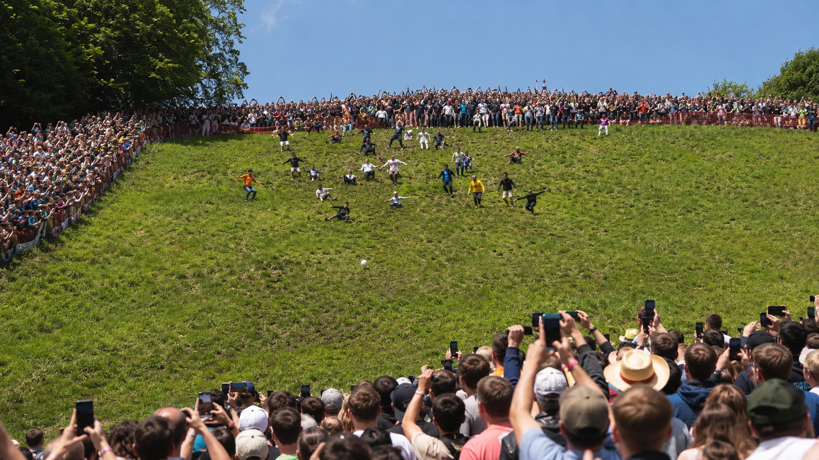 Une foule de spectateurs alignee en haut d'une colline verte regarde la descente, telephones leves.