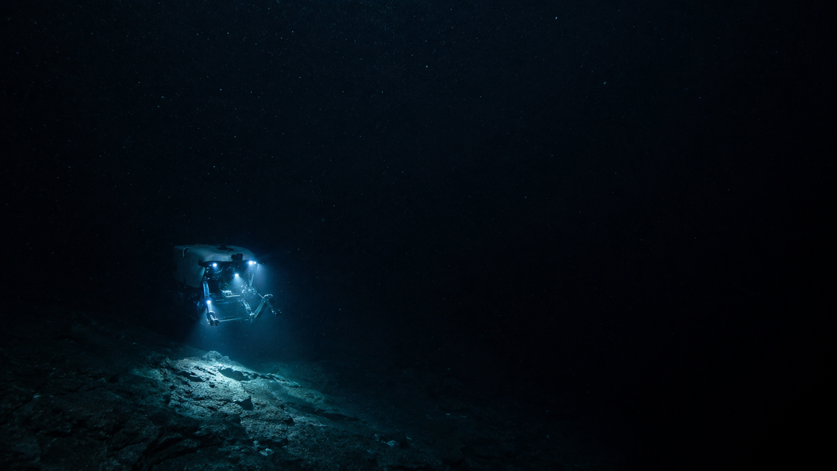 Sous-marin habité de grands fonds explorant un plancher océanique sombre, bras mécaniques déployés