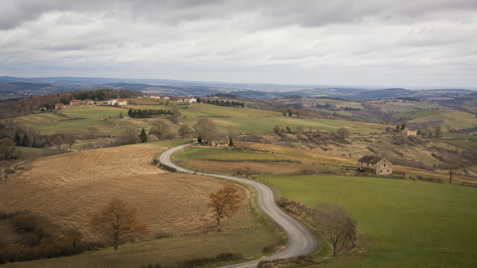 Route de campagne sinueuse entre des fermes isolées et espacées