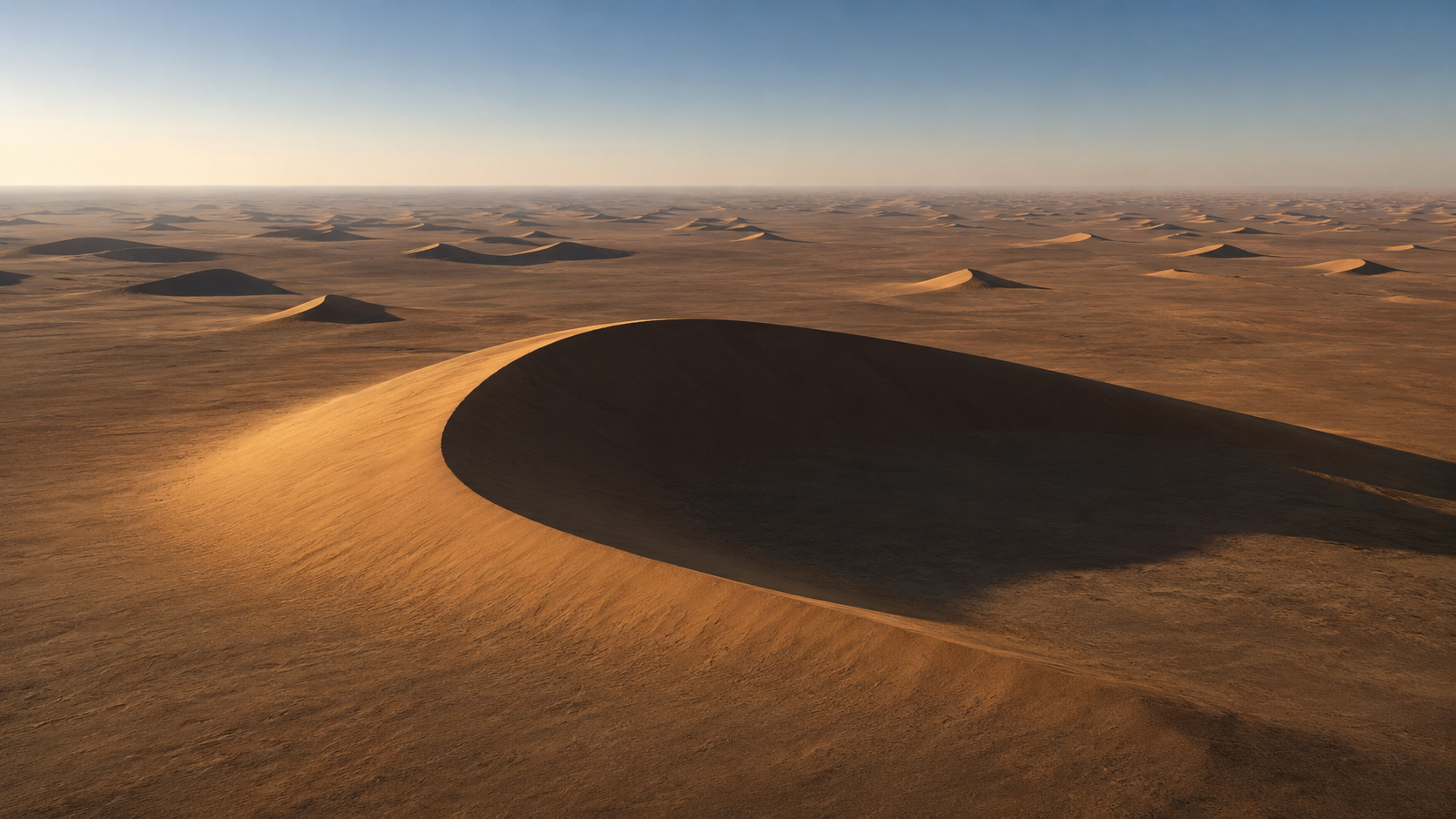 Champ de dunes en croissant s'étendant jusqu'à l'horizon sous un ciel dégagé