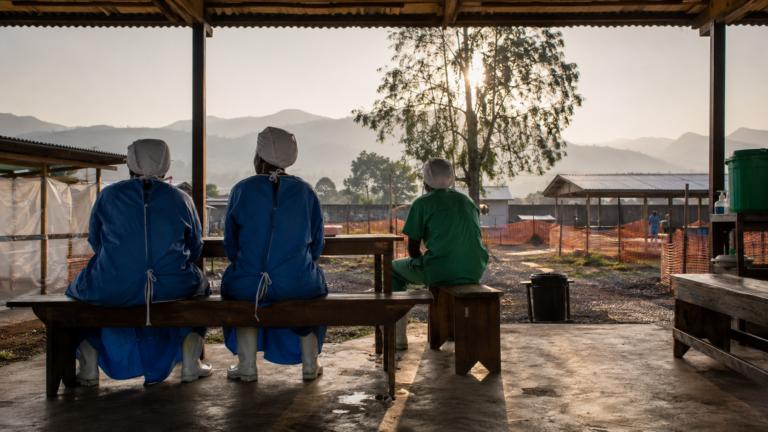Cour d’un centre de soins en Afrique centrale avec soignants de dos