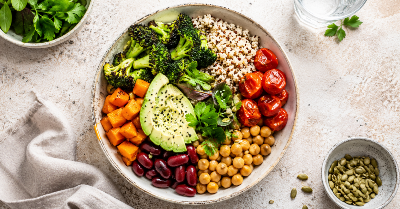 un bol coloré de légumineuses, légumes et céréales complètes vu de dessus, sur une table claire