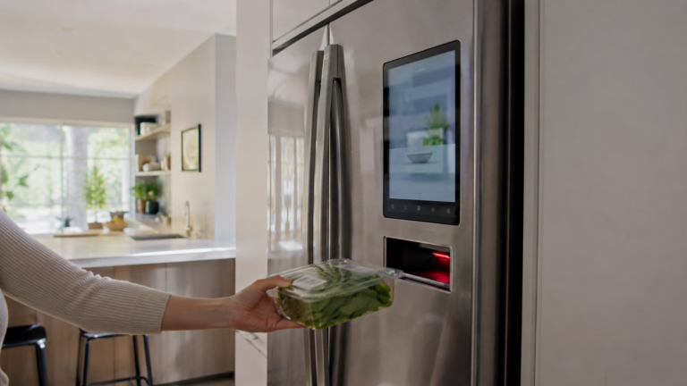 Réfrigérateur connecté inox avec écran et lecteur de code-barres sur la porte, une main approchant un produit