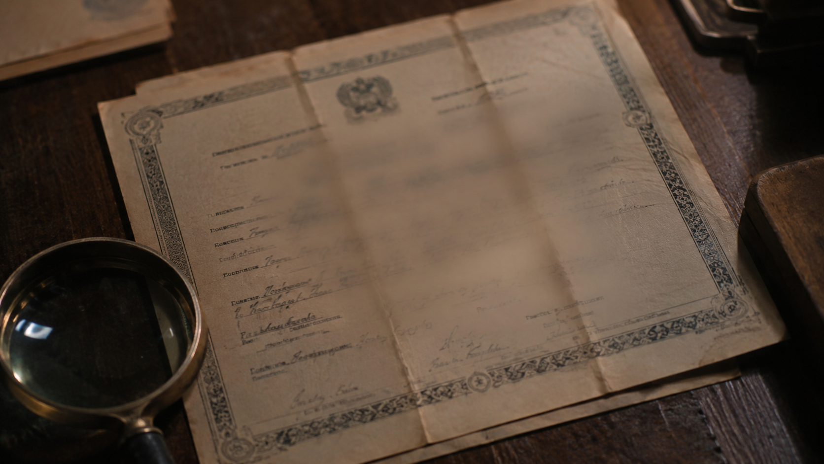 Un acte de naissance ancien posé sur un bureau avec une loupe, la date floutée