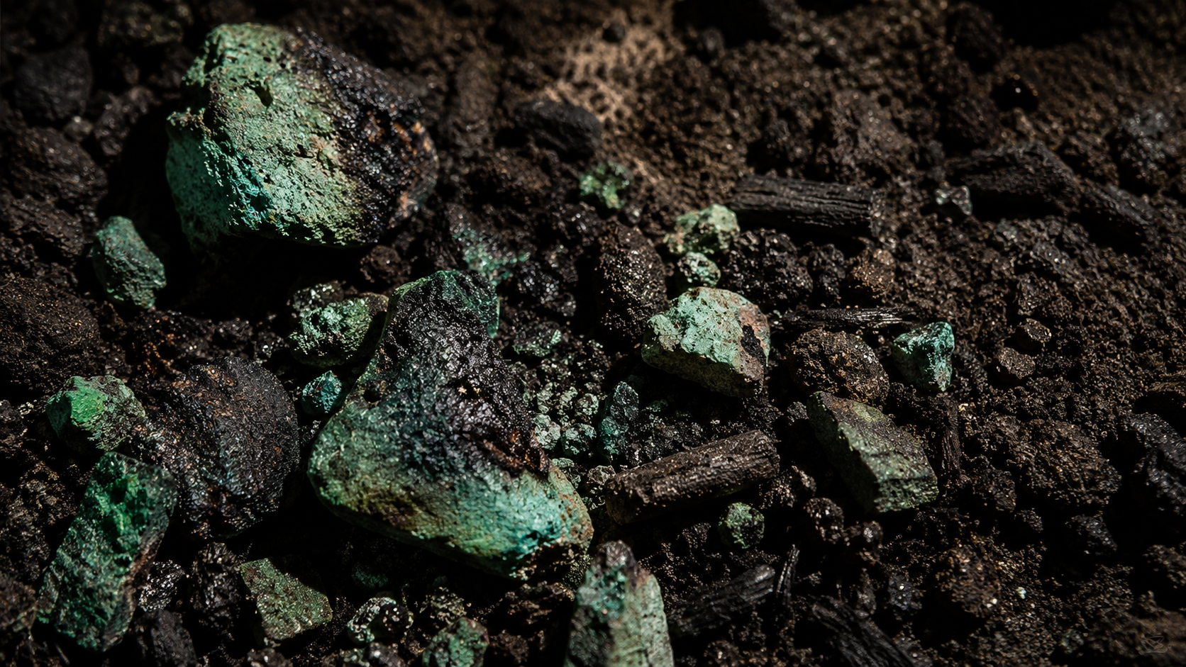 Fragments de minéral vert broyés posés sur le sol sombre d'une grotte