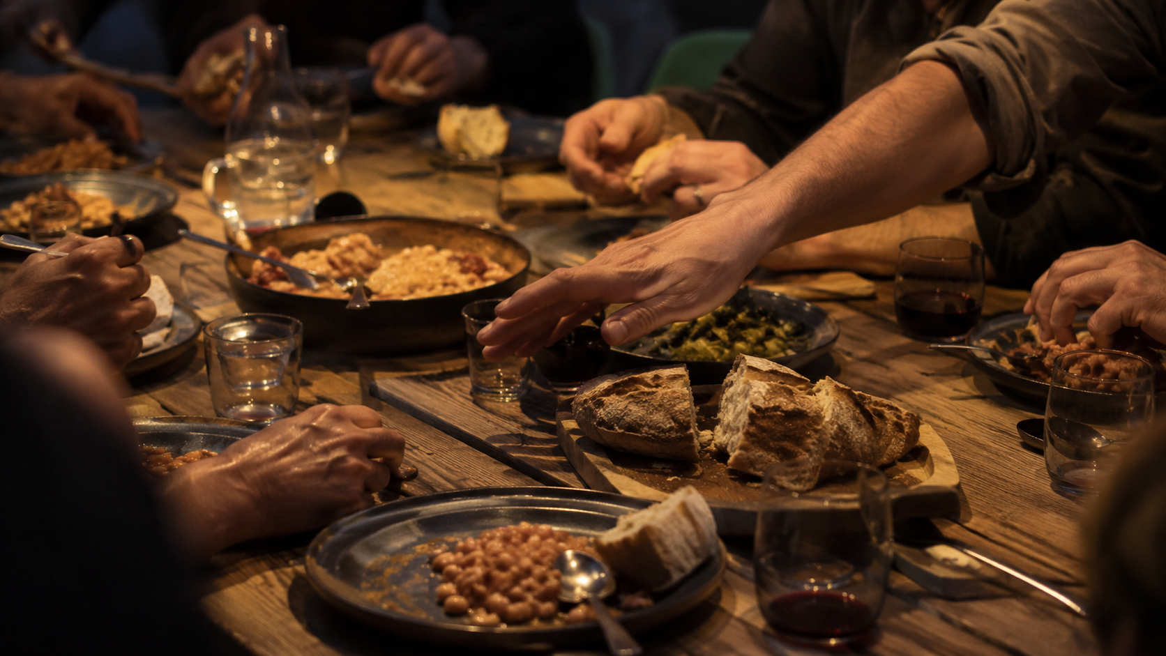 Plusieurs personnes partagent un repas simple autour d'une table en bois après le chantier