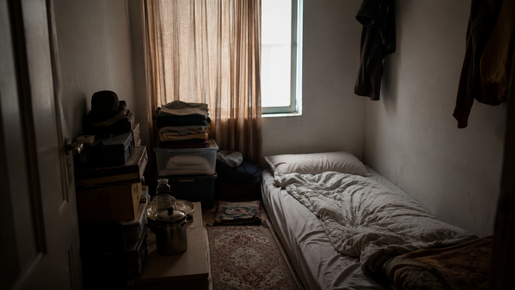 Petite chambre surpeuplée avec matelas au sol et affaires empilées