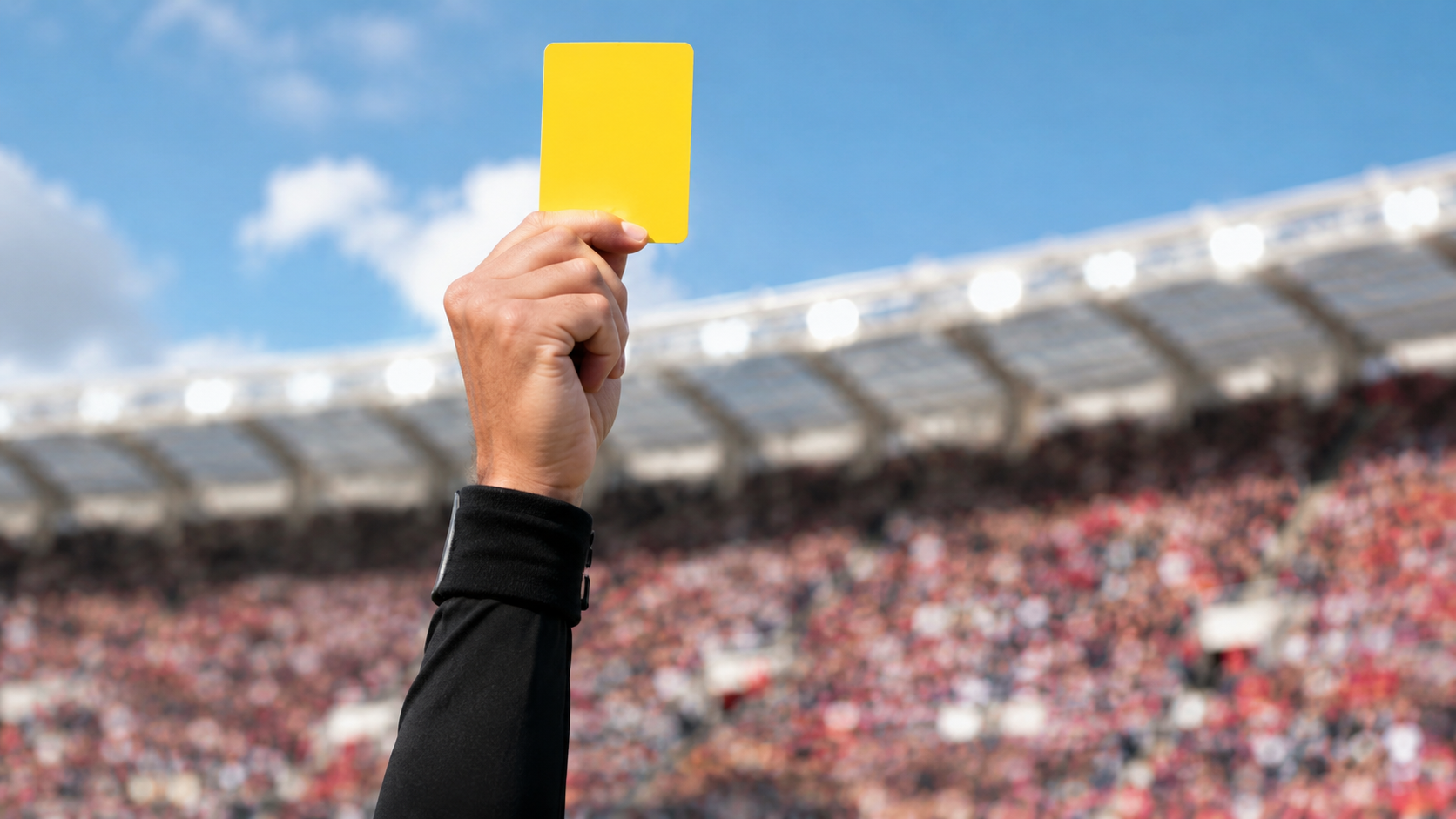 Main d'arbitre brandissant un carton jaune dans un stade