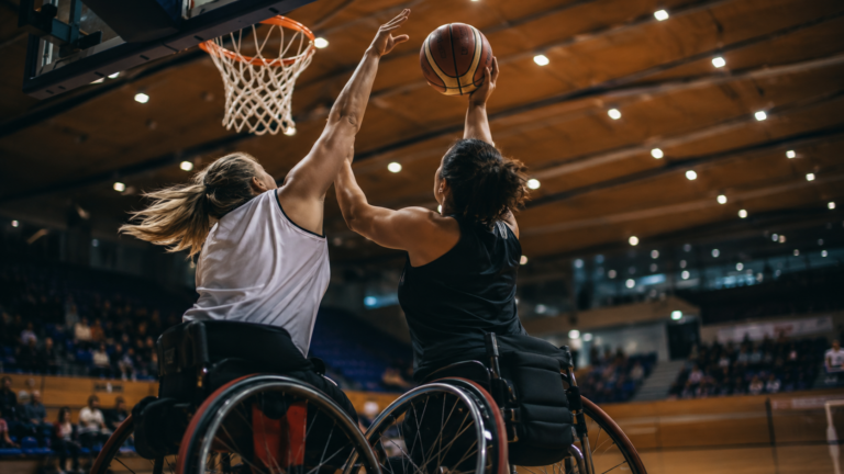 Joueuses de basket fauteuil disputant un ballon sous le panier dans une salle de competition