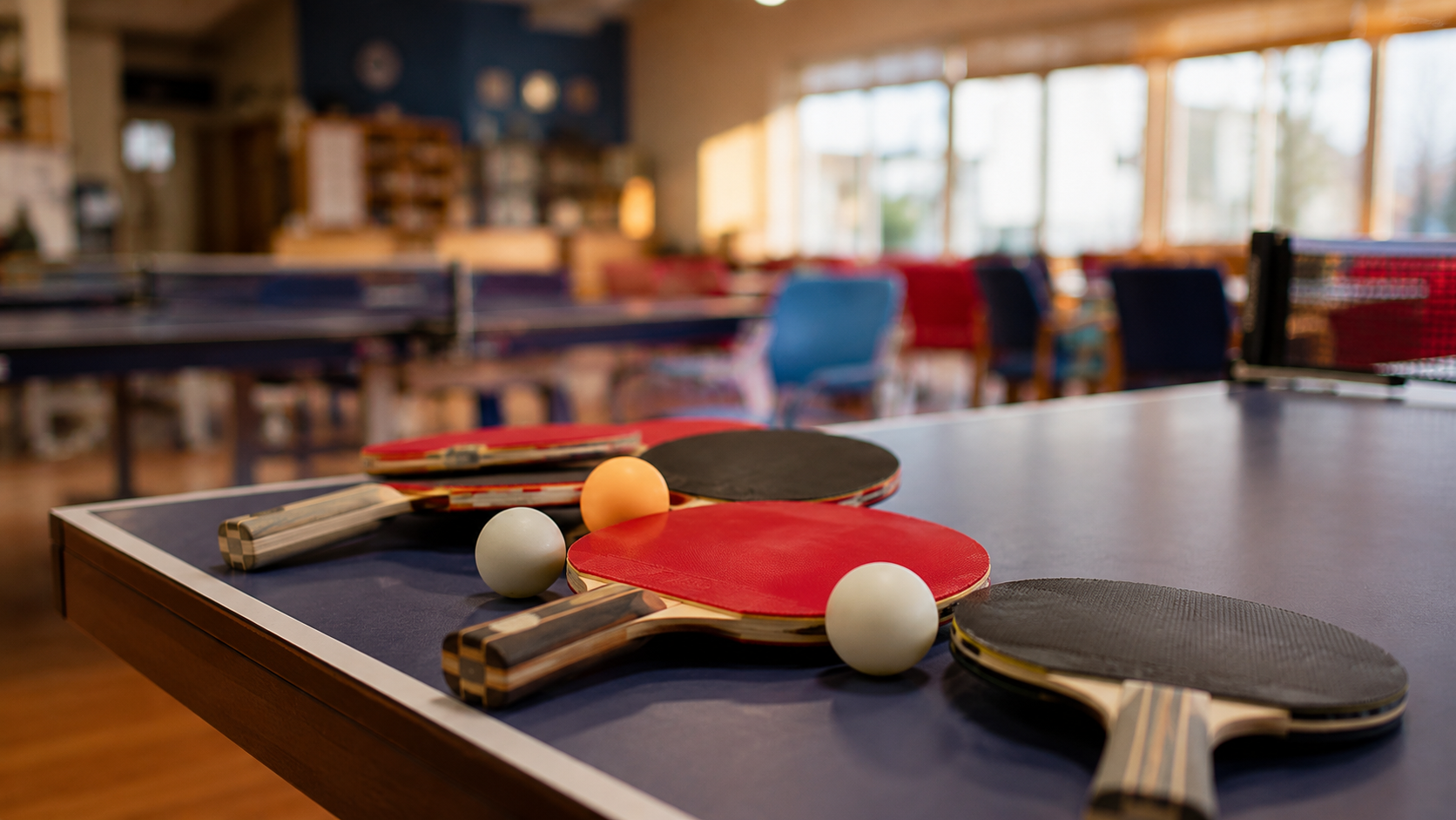 plusieurs raquettes et balles posées sur le bord d'une table de club, salle conviviale en fond flou