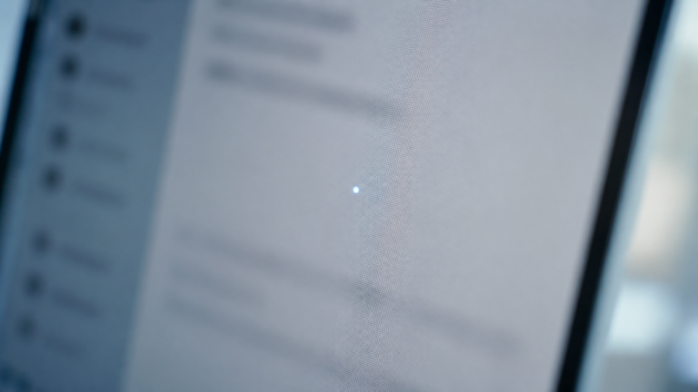 Gros plan macro d'un écran de messagerie, un point lumineux minuscule isolé dans le blanc d'un mail