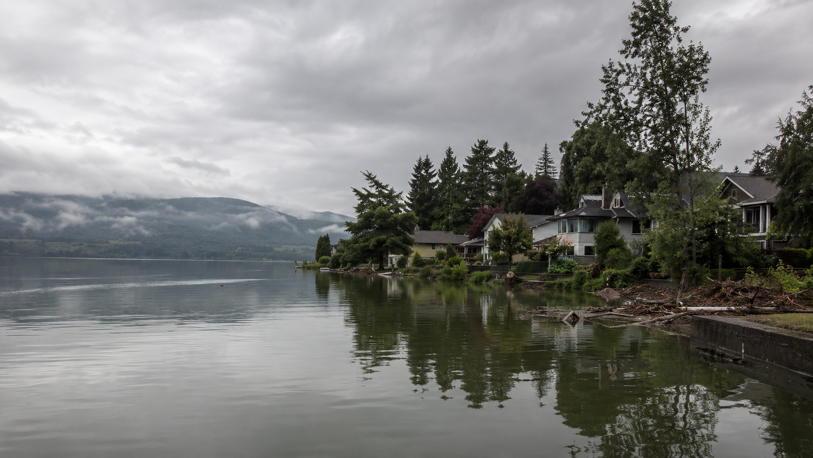 Une petite ville au bord d'un lac entourée d'arbres, l'eau montée près des jardins après une crue