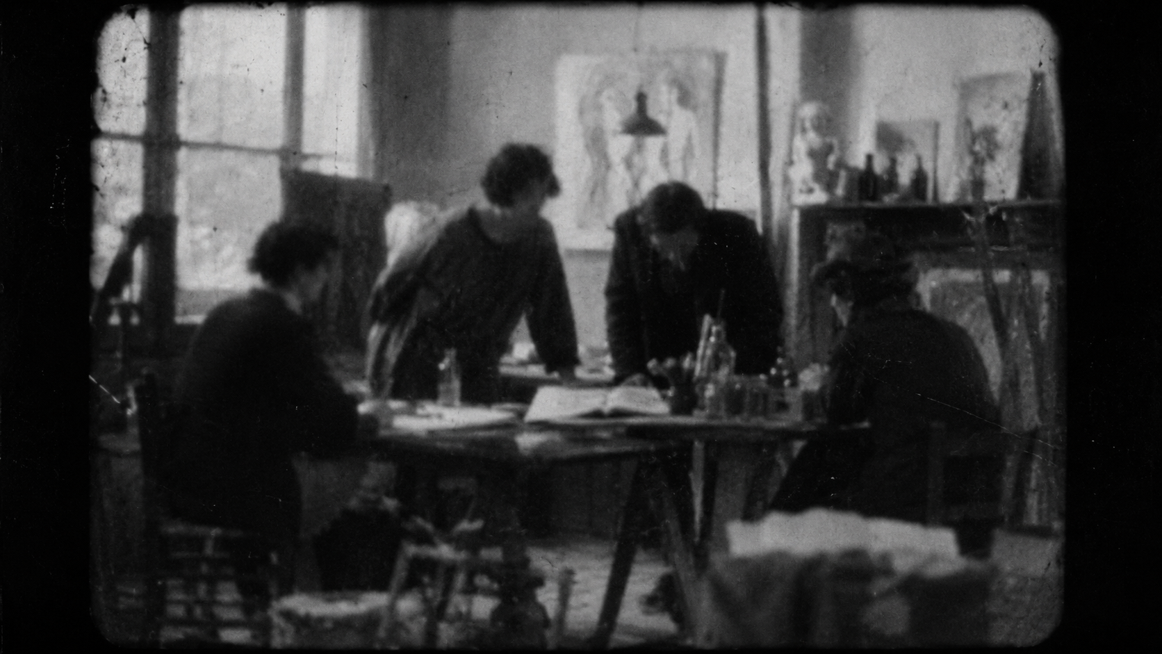 Photogramme noir et blanc granuleux évoquant un film amateur muet des années 1920, silhouettes d'artistes autour d'une table