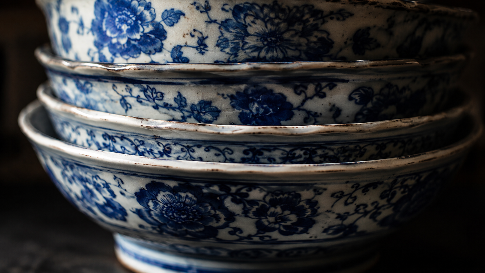 Le gros plan de bols anciens en porcelaine bleu-et-blanc empilés, à motifs floraux