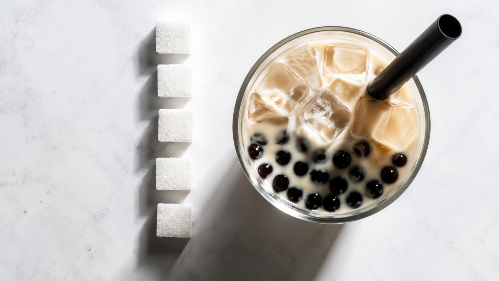 Cubes de sucre alignés devant un verre de bubble tea pour illustrer la teneur en sucre
