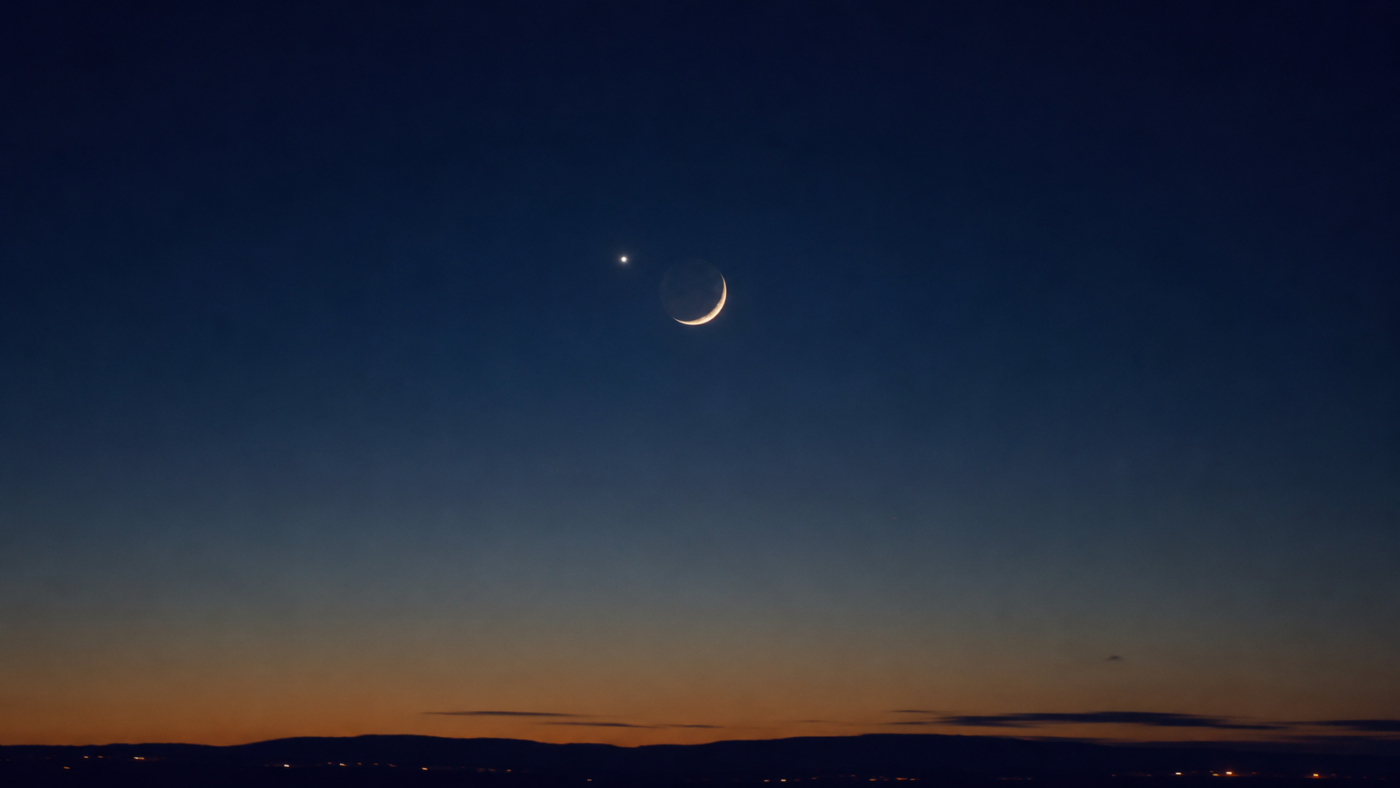Un croissant de Lune dans un ciel bleu avec Vénus brillante juste à côté.
