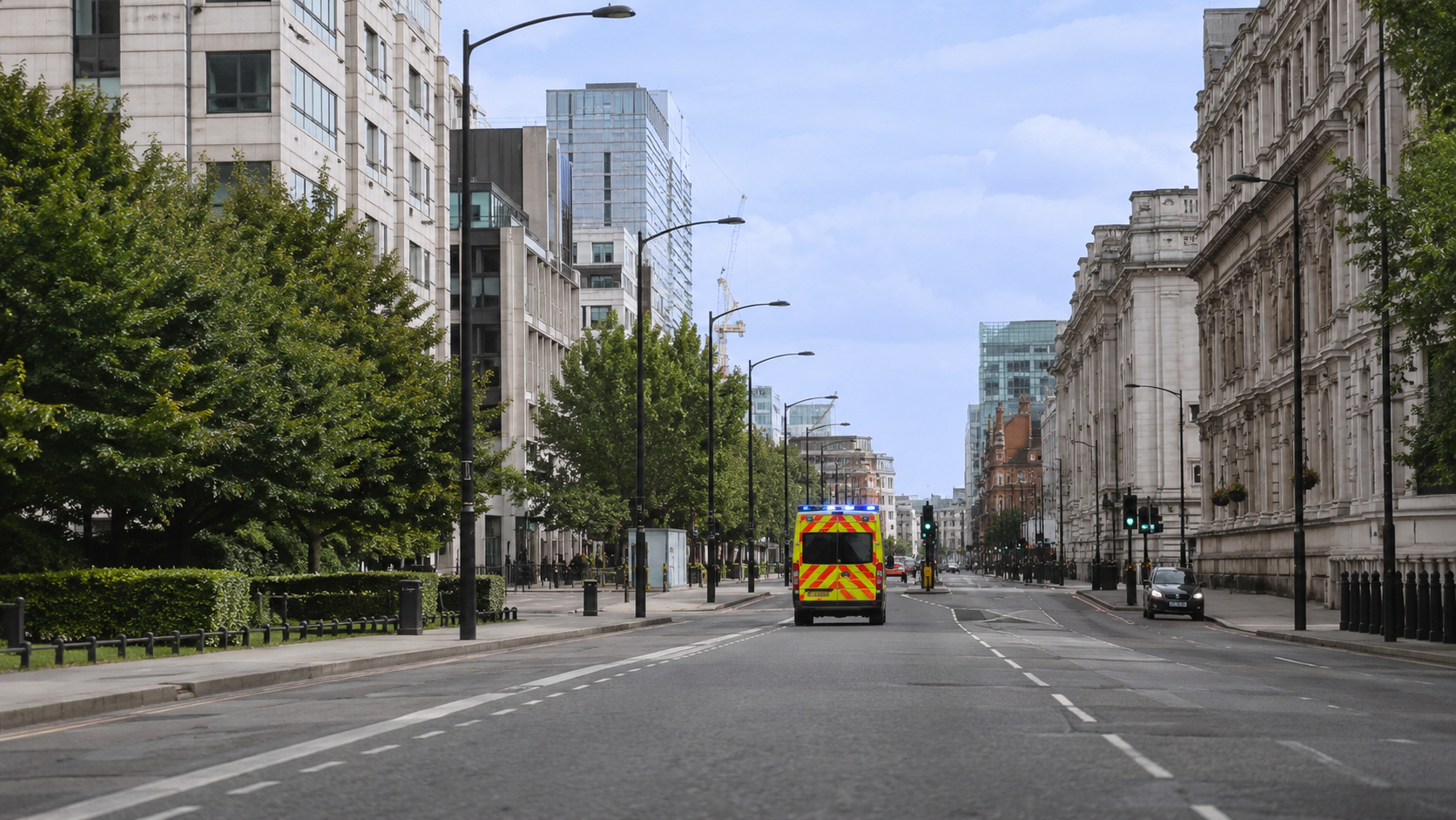Une ambulance vue de loin s'eloignant sur une large avenue urbaine en plein jour