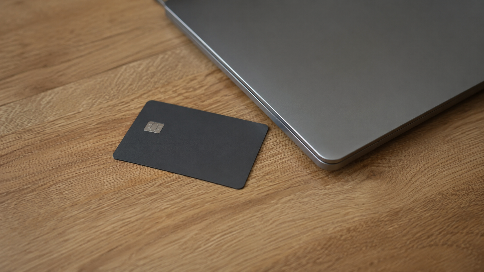 Une carte bancaire posée sur une table près d'un ordinateur portable.