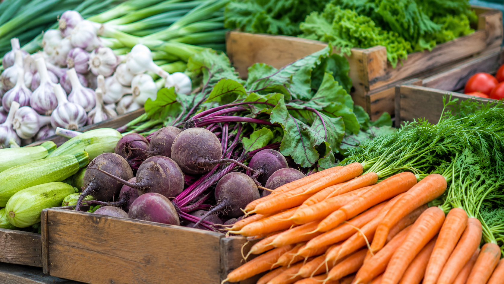 Un étal de marché avec des cagettes de légumes de saison colorés.