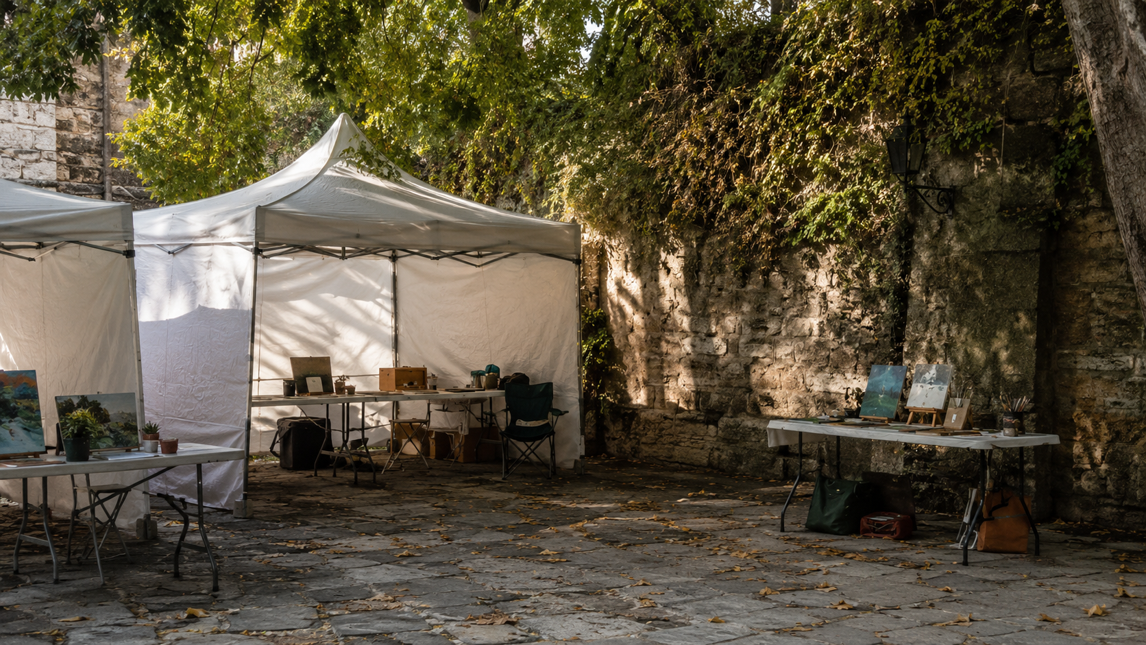 Campement de tentes d'artistes et tables pliantes dans un coin ombragé près du festival.