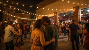 Bal populaire nocturne dans une cour de caserne eclairee de guirlandes, foule qui danse