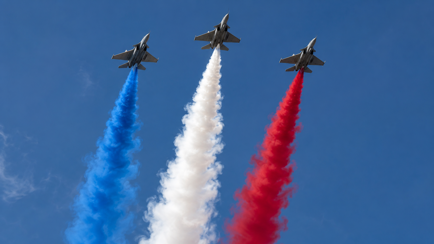 Trois avions de chasse laissant une traînée de fumée tricolore dans un ciel dégagé